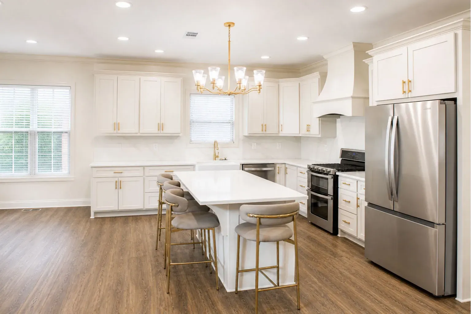 Modern Seating Island: Showcases a sunlit seating island, crisp white cabinetry, a gold statement chandelier, and matching luxury hardware.