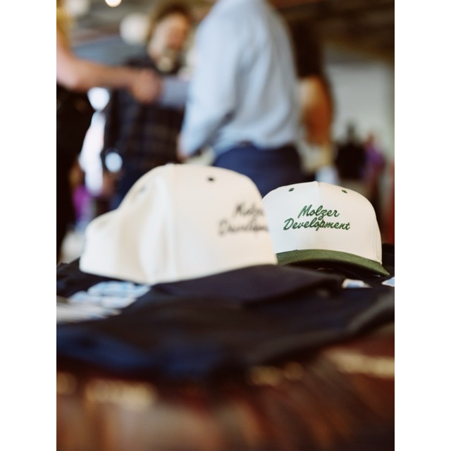 Branded merchandise and apparel showcasing Molzer Development’s identity at a community-focused real estate development event in Kansas City.