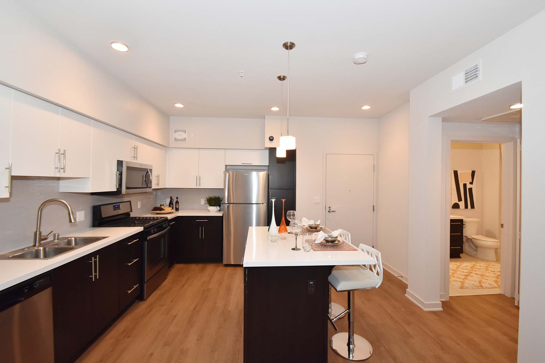A modern kitchen with dark wood floors and white countertops.