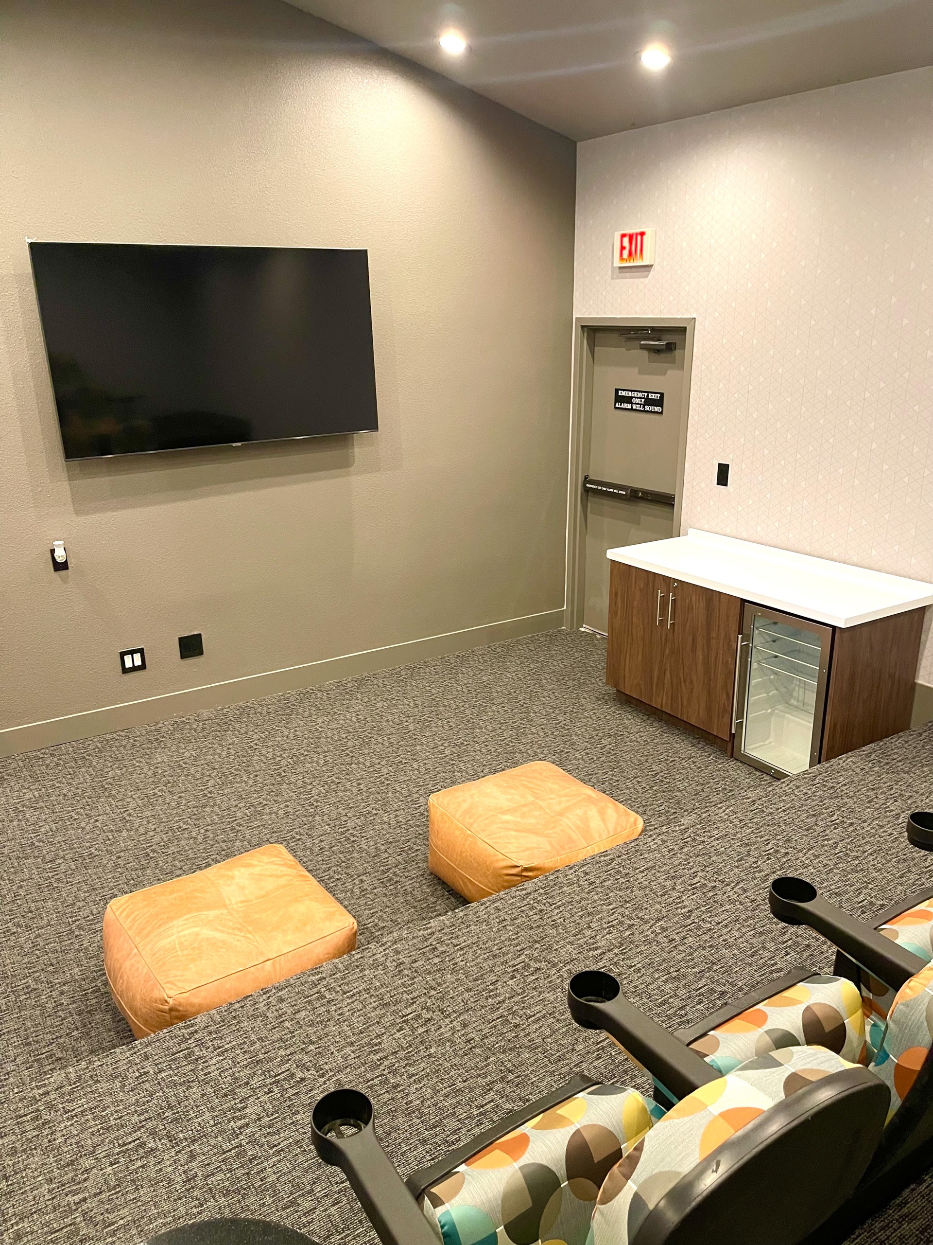 A conference room with a TV, chairs, and a white table.
