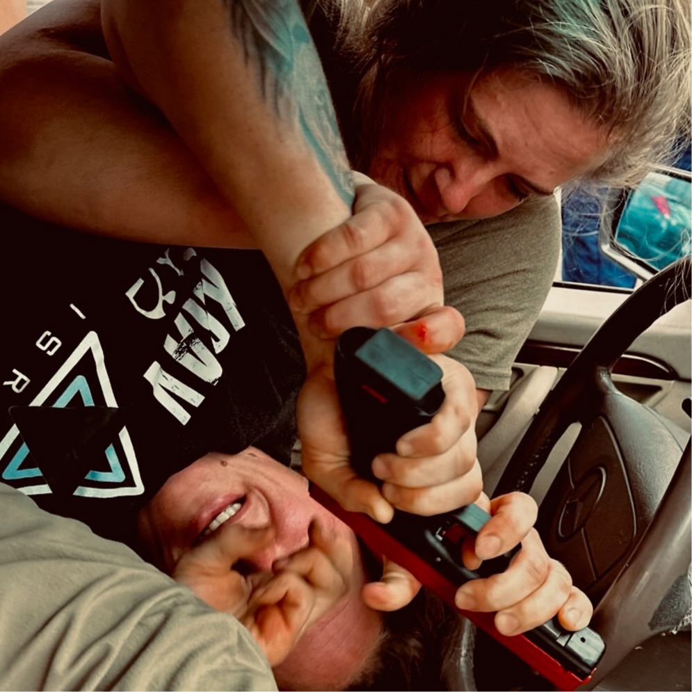 Students drilling a weapon defense scenario inside a vehicle, practicing how to respond to a threat in a confined space.