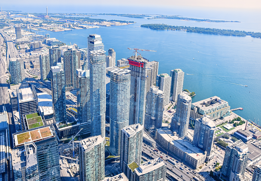 Aerial view of downtown waterfront with tall skyscrapers overlooking blue lake and boats.