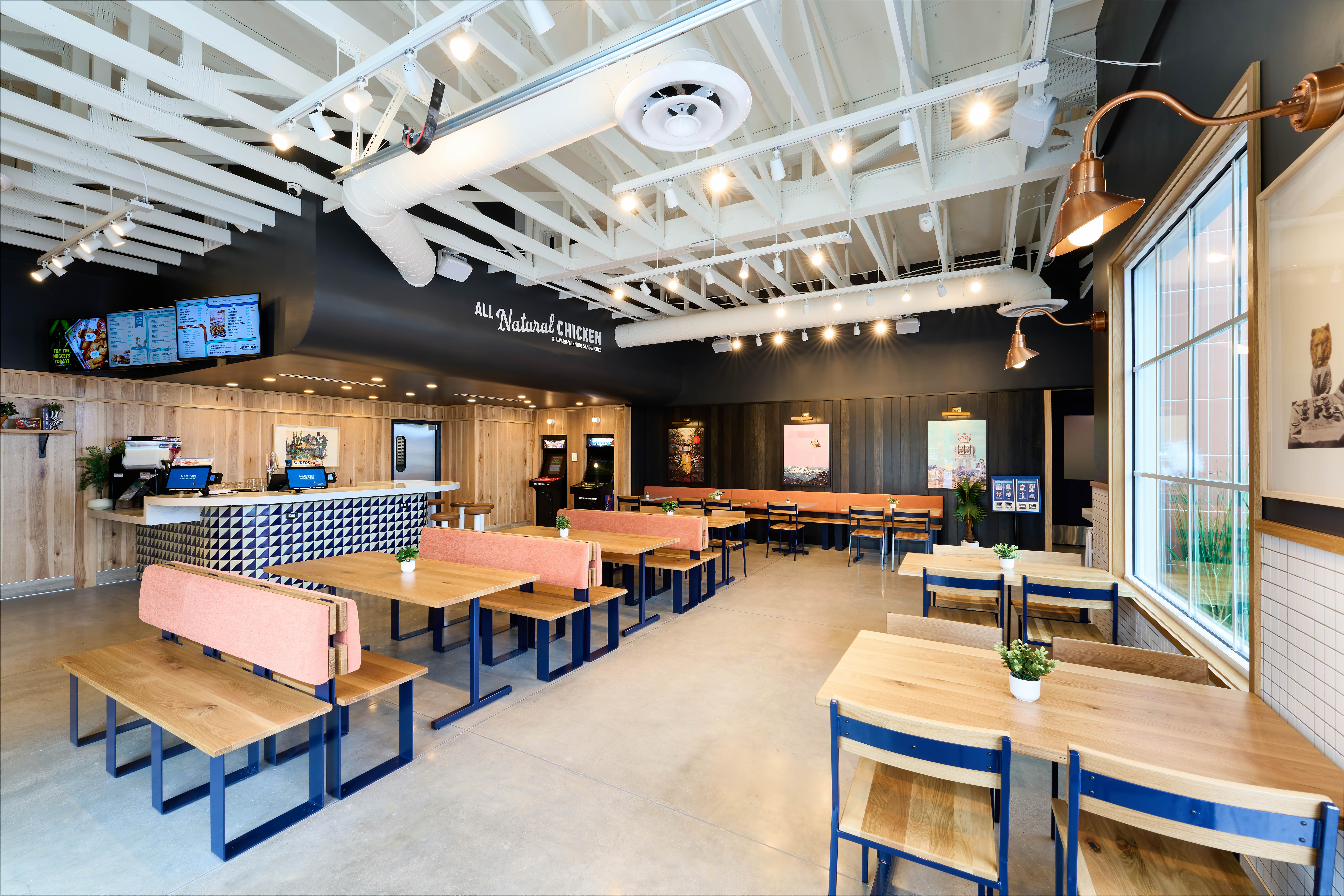 Interior view of dining room, highlighting the booths, ordering system, sticker vending machine, and free-play arcade games.