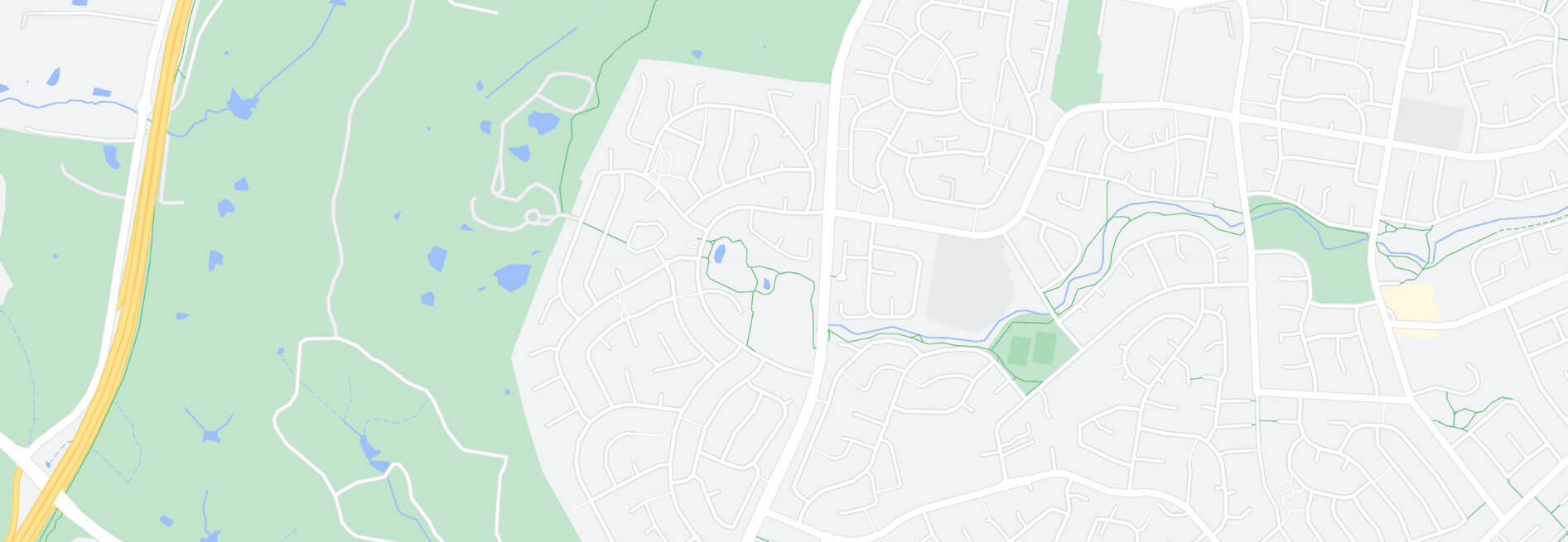 A map of a suburban area showing roads, green spaces, and bodies of water. A highway runs along the  