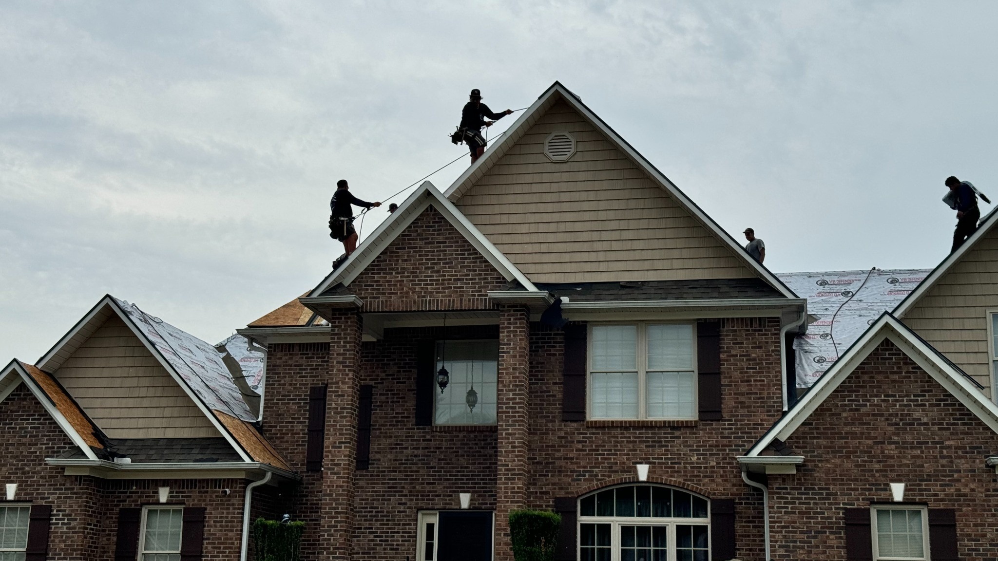 A State 8 Roofing crew performs a residential roof replacement on a two-story brick home in Upstate South Carolina. Professional roofers are installing a new asphalt shingle roofing system using proper safety equipment and fall protection. State 8 Roofing specializes in roof replacement, roof repair, storm damage restoration, roof inspections, and high-quality residential roofing services throughout Greenville, Simpsonville, Greer, Mauldin, Spartanburg, and the surrounding Upstate South Carolina communities.