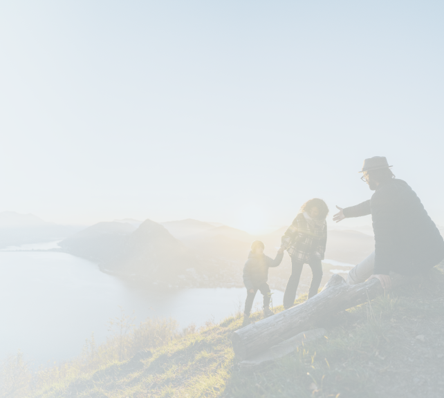 Une famille gravissant une montagne ensemble, avec une vue magnifique en arrière-plan.