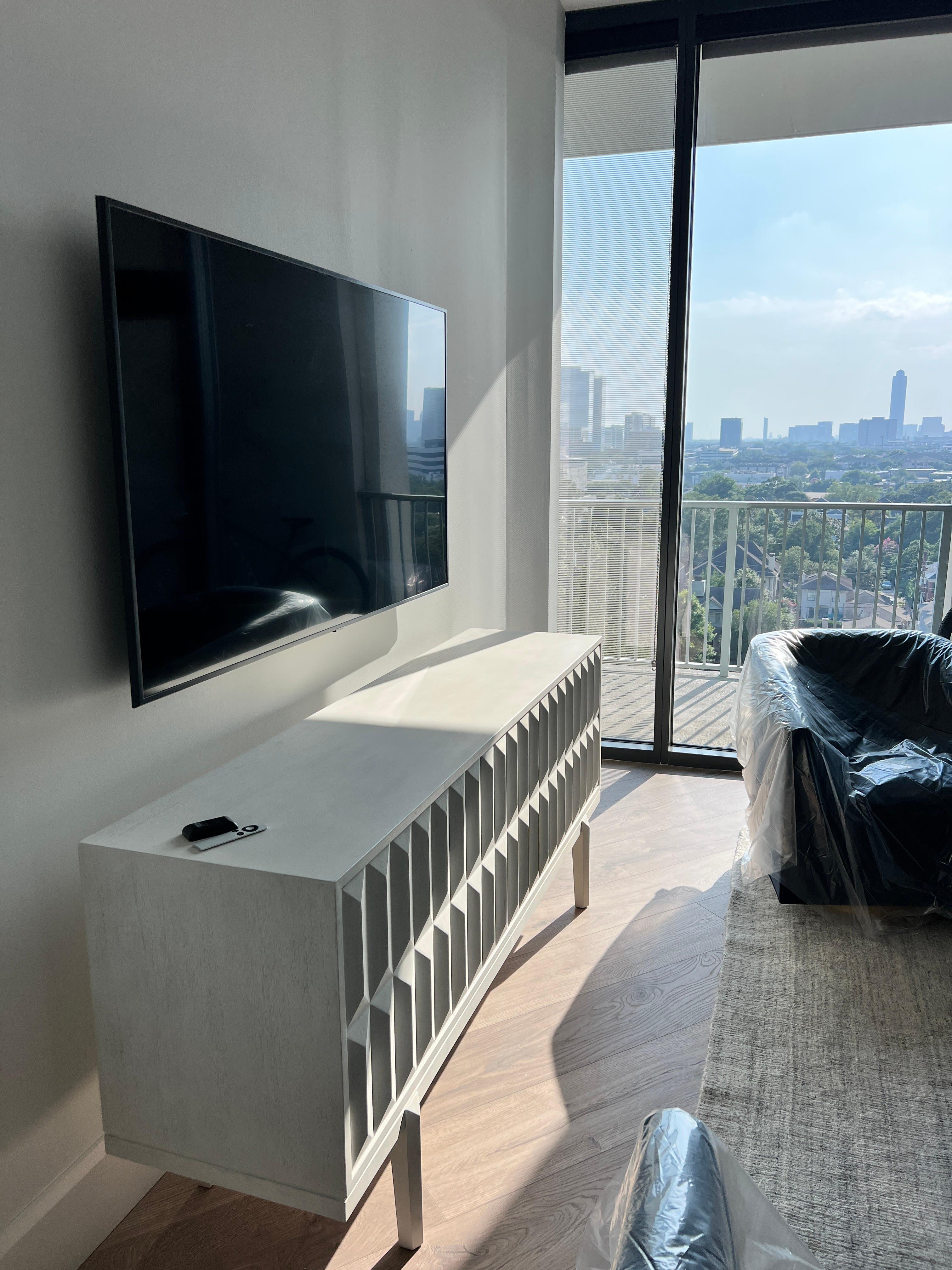Flat-screen TV mounted on a living room wall in a Houston high-rise apartment.