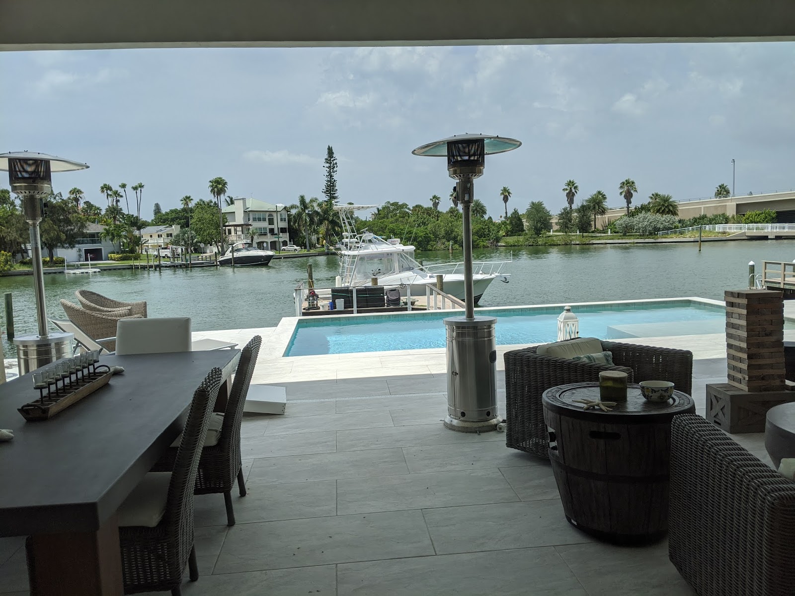 Waterfront pool and outdoor living area with covered dining space, patio seating, and scenic views across the water.