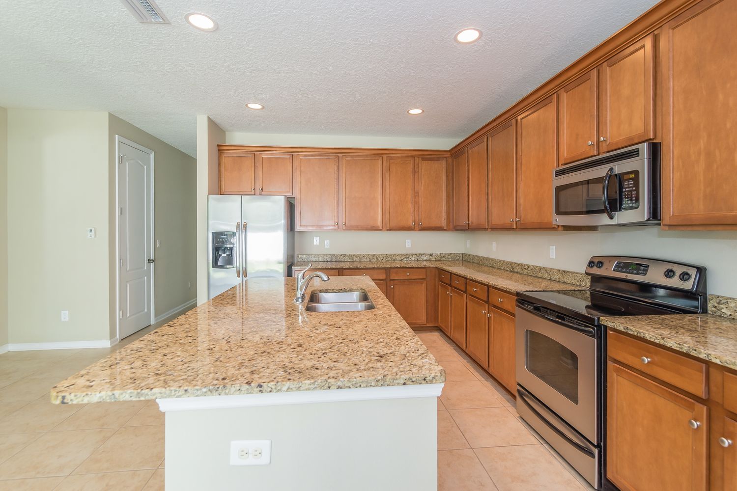 Spacious kitchen with an island, stainless steel appliances, and recessed lighting at Invitation Homes Jacksonville.