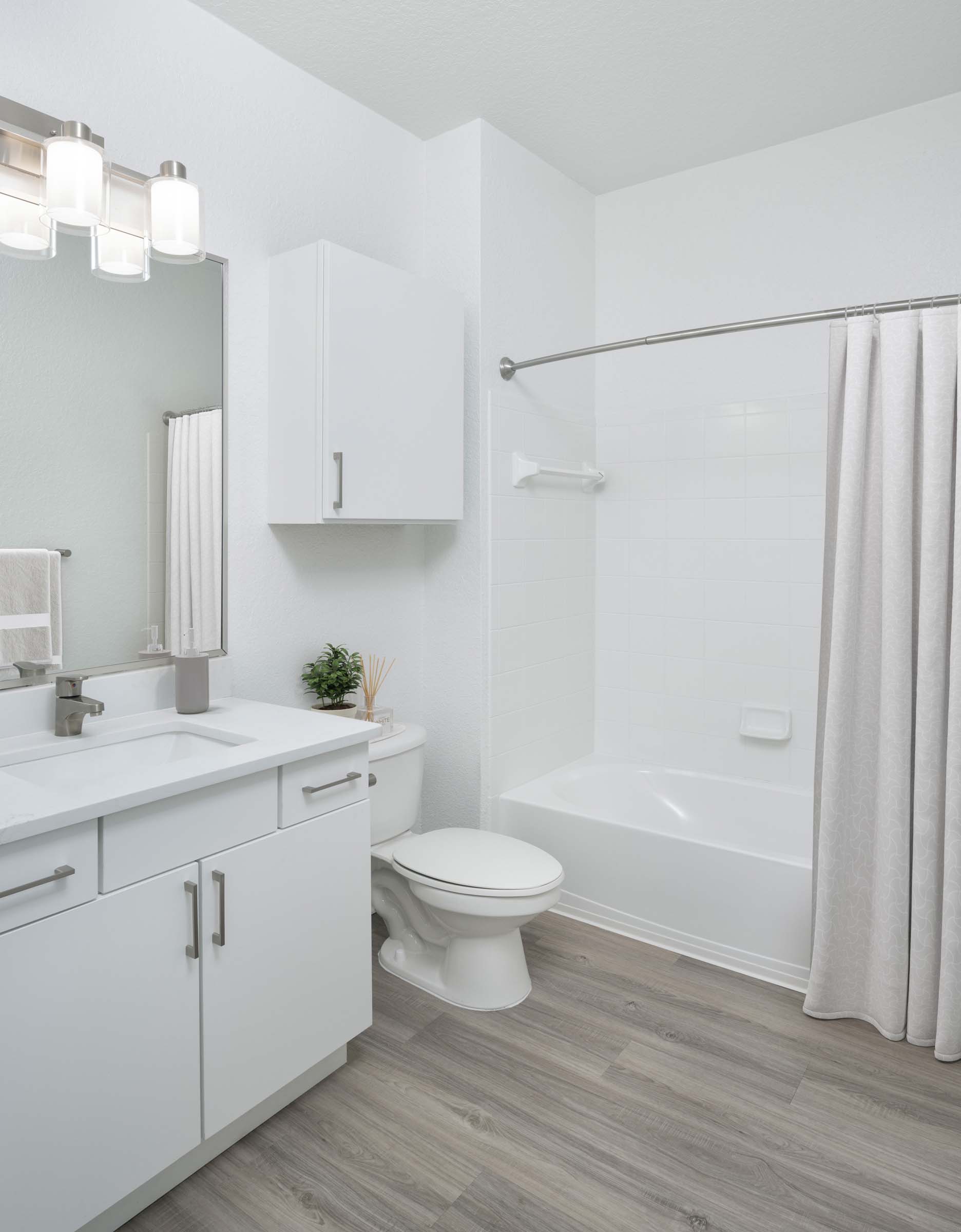 Bathroom with white quartz countertops, white cabinets and bathtub at Camden World Gateway apartments in Orlando, FL