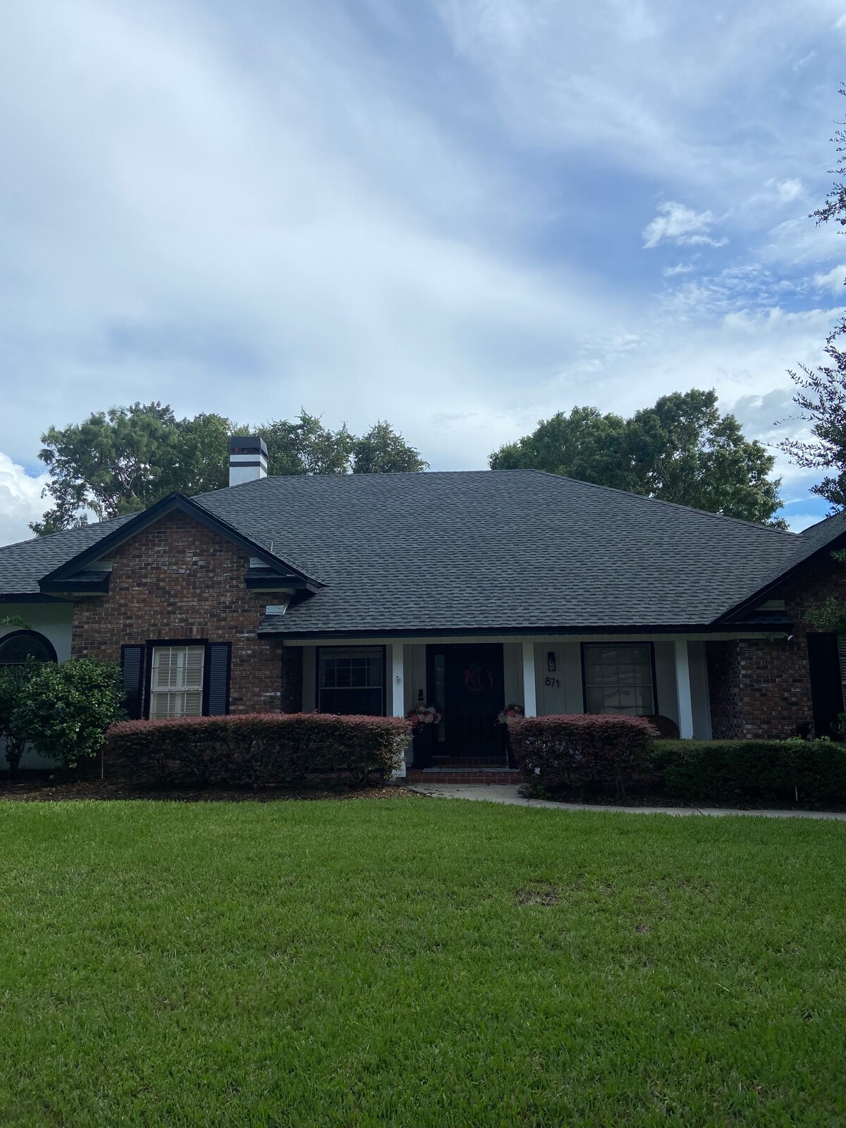 Front view of a completed dark asphalt shingle roof on a single-story brick home.