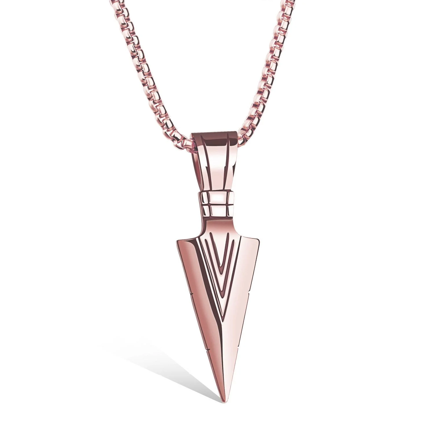 A close-up, studio shot shows a rose gold arrowhead pendant necklace against a white background. The pendant is detailed with etched lines forming a chevron pattern. The chain is a classic box link style, also in rose gold.