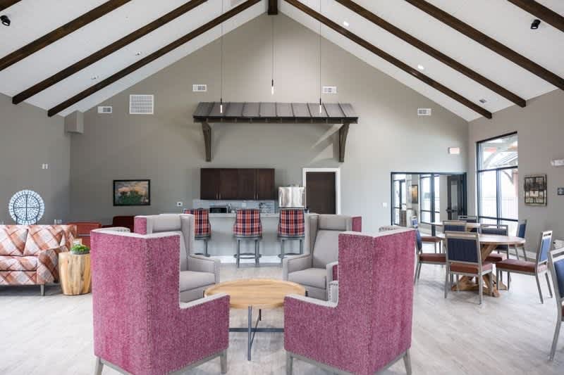A room with a pink chair in the foreground and a couch in the background.