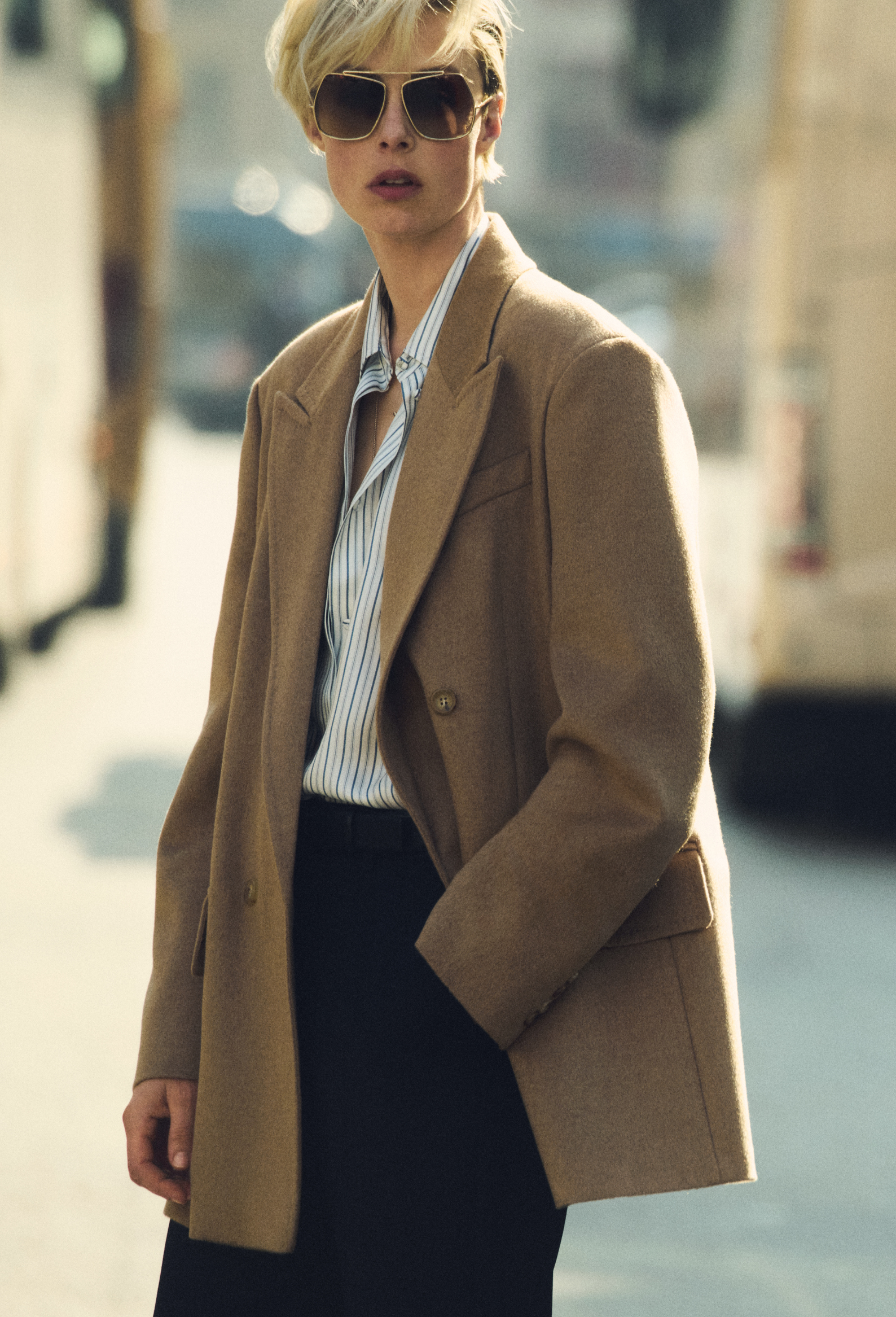 Modella in blazer doppiopetto Olimpia Jacket di Max Mara color cammello, con occhiali scuri e camicia in contesto urbano.