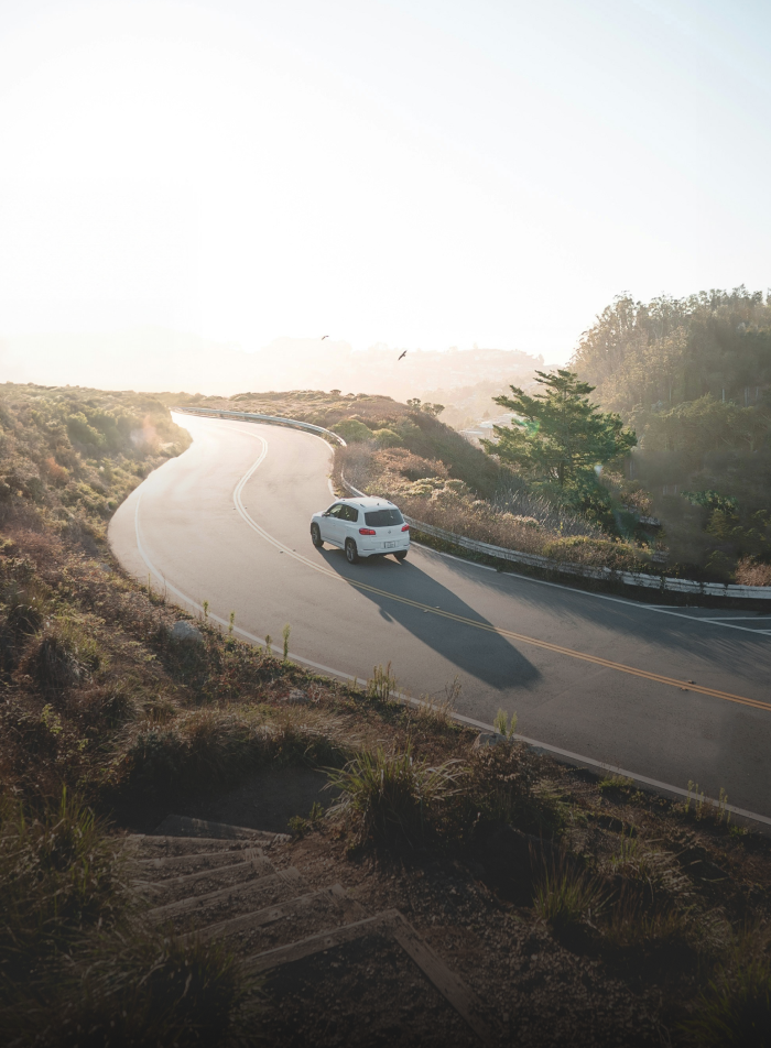 An aerial shot of a car driving along a winding road.