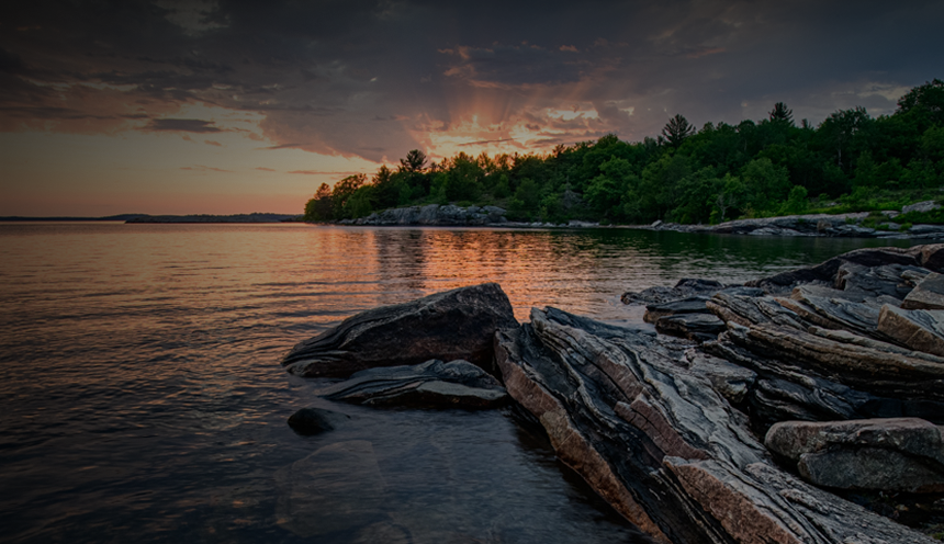 Close up of a rocky shore and calm water at sunset.