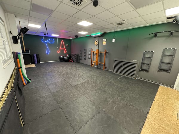 TA WingTsun Seelze - Großer Mattenraum mit schwarzem Boden, Trainingswand, Balancebällen und funktionalem Equipment für Selbstverteidigung, Kampfsport und gezieltes Techniktraining.