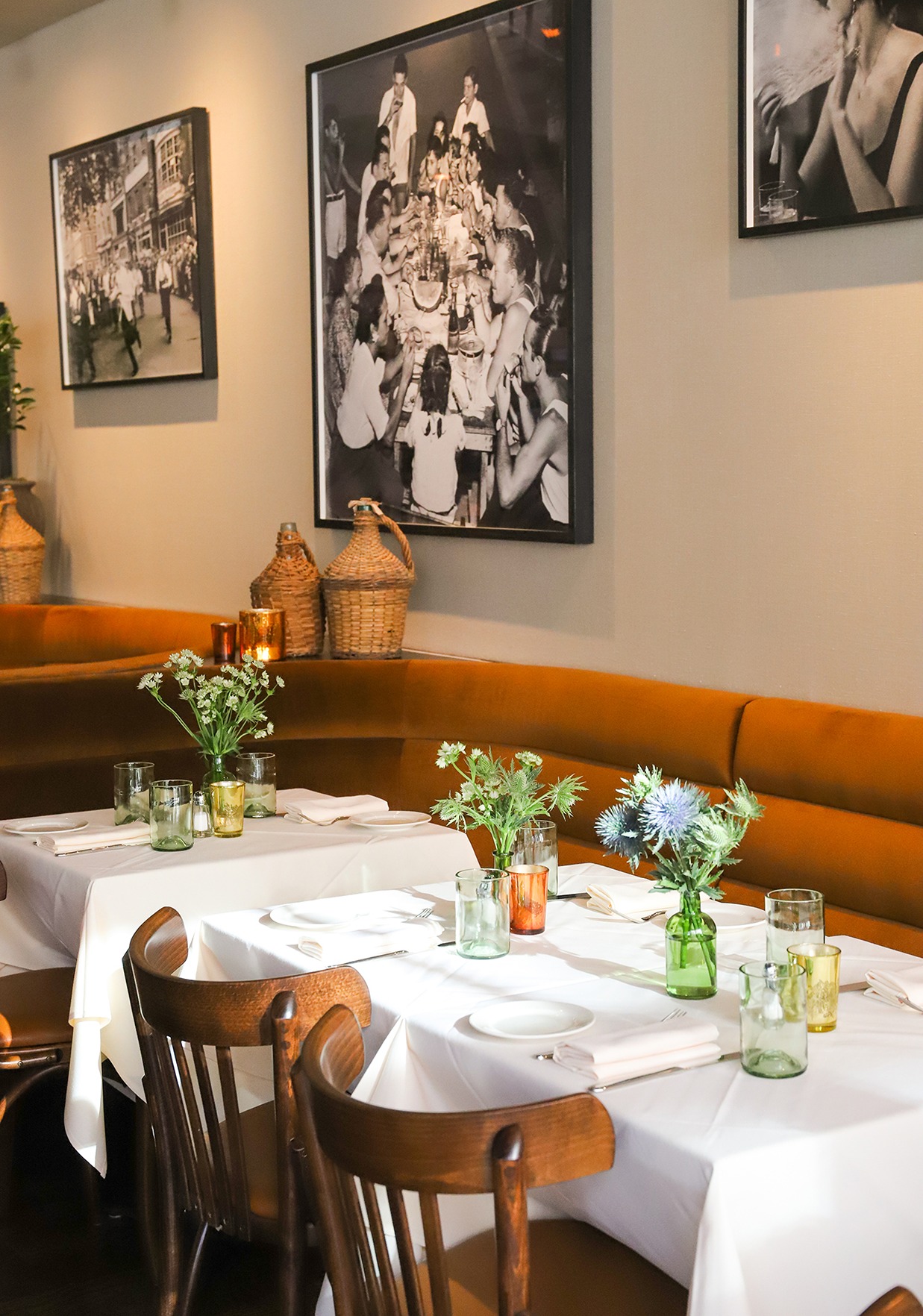 The interior of Felice Montague featuring cognac-colored velvet banquettes, crisp white linens, and nostalgic black and white photography.