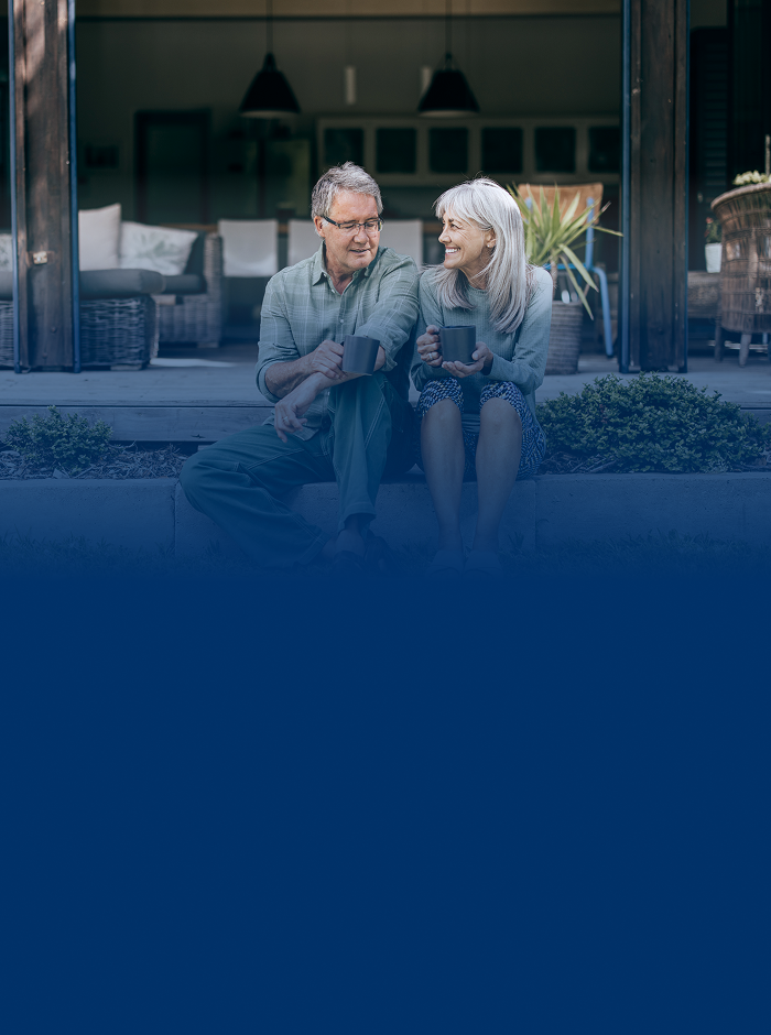 A retired couple sitting on their front porch with a mug in hand.