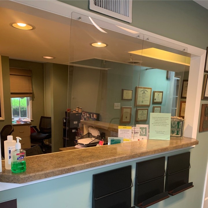 Reception desk in a dental office with a glass wall, featuring a welcoming atmosphere for patients.