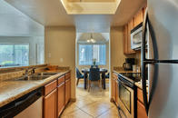 Kitchen with stainless steel appliances, faux granite counters, cherry shaker cabinets, and tile.