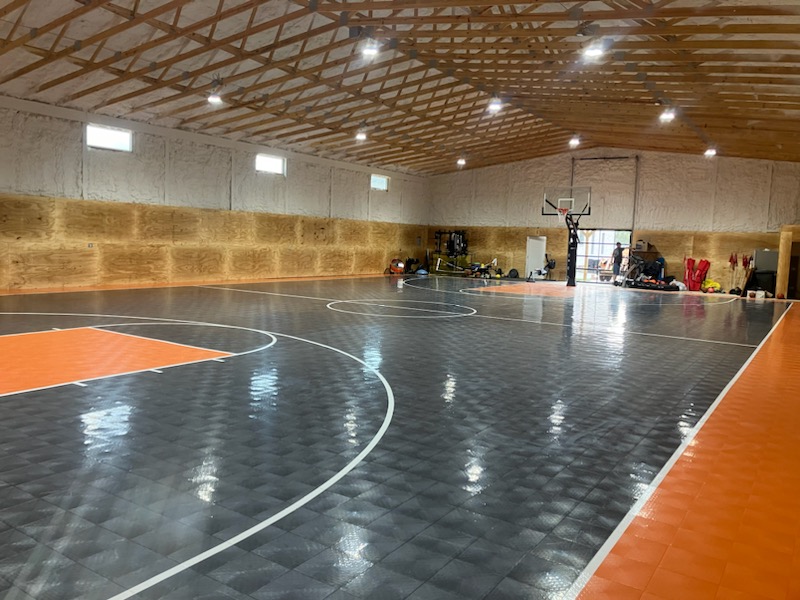 Full-size indoor multi-sport court with basketball hoop.