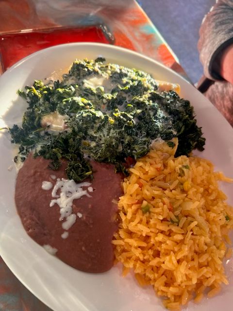Spinach and cheese enchiladas topped with a creamy spinach sauce and served with Mexican rice and refried beans at Catramex Restaurant.