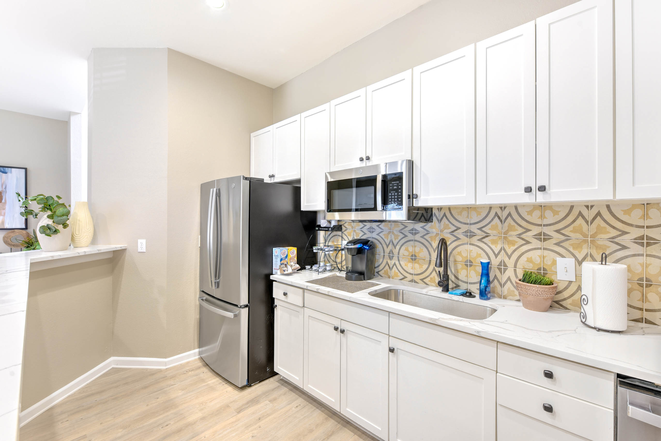 Community kitchen with white cabinets and a stainless steel fridge