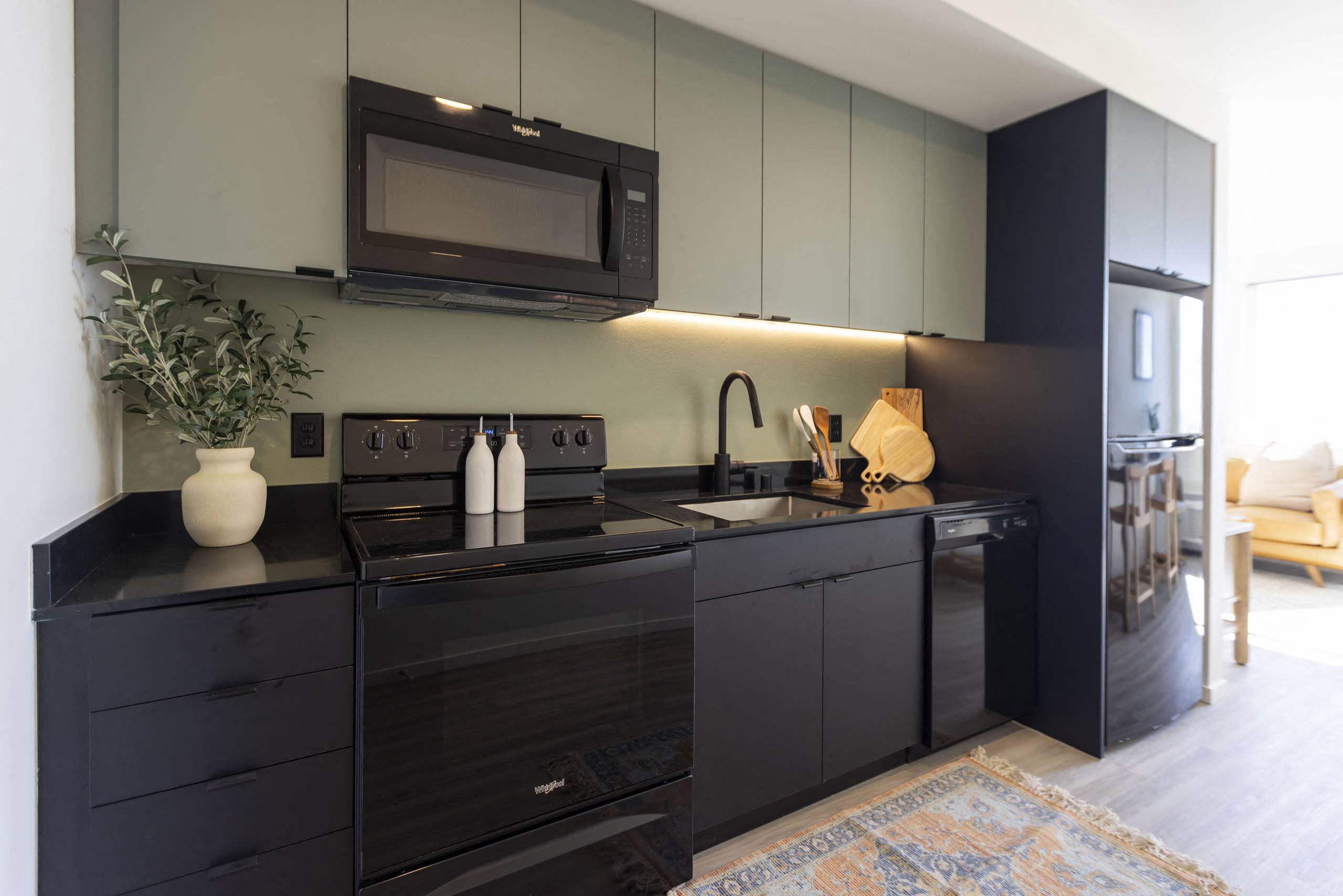 a kitchen with black cabinets and a sink and a microwave