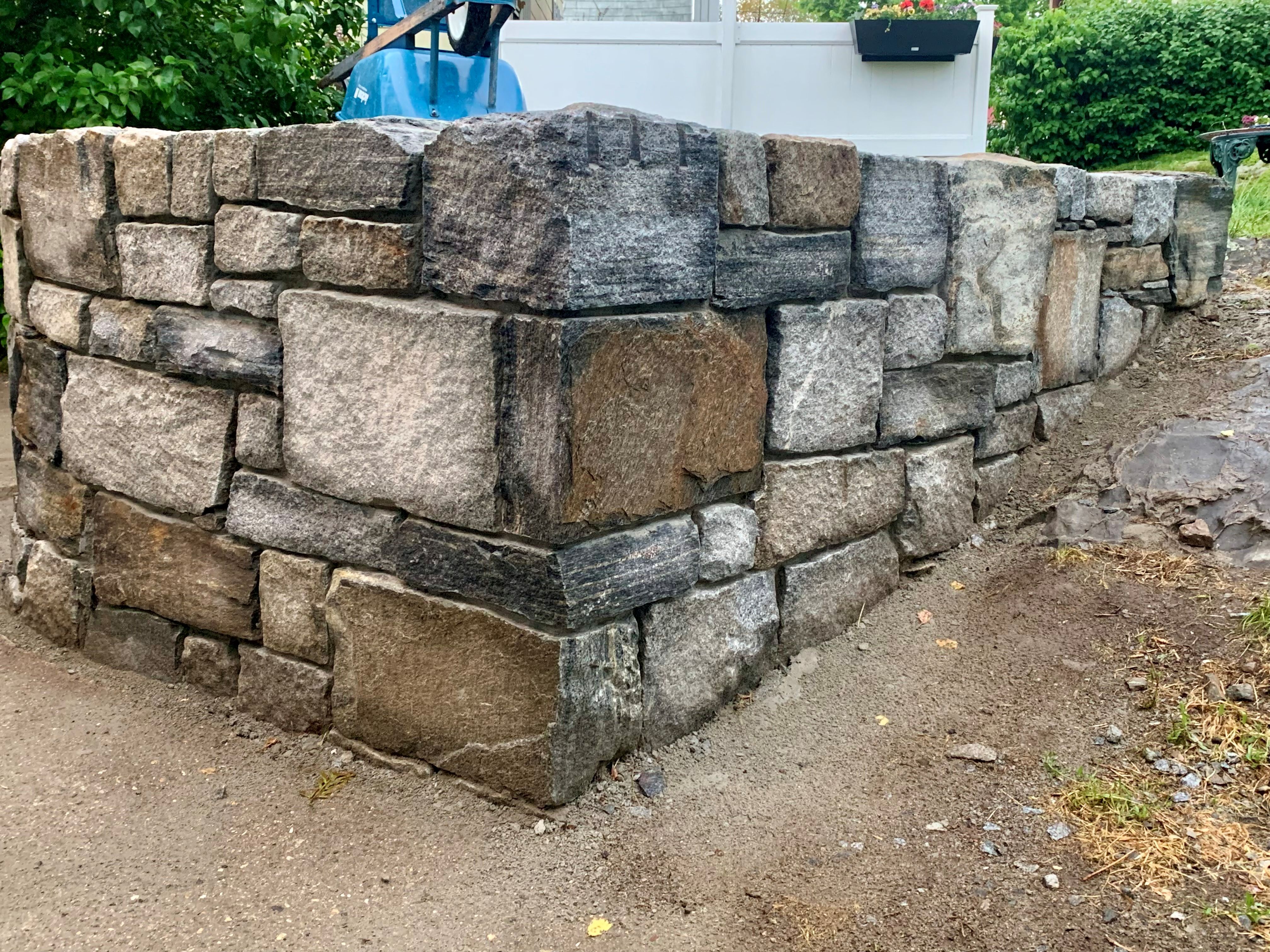 Custom granite retaining wall built by Mac's Masonry using natural stone blocks for lasting strength, drainage support, and a timeless New England appearance.