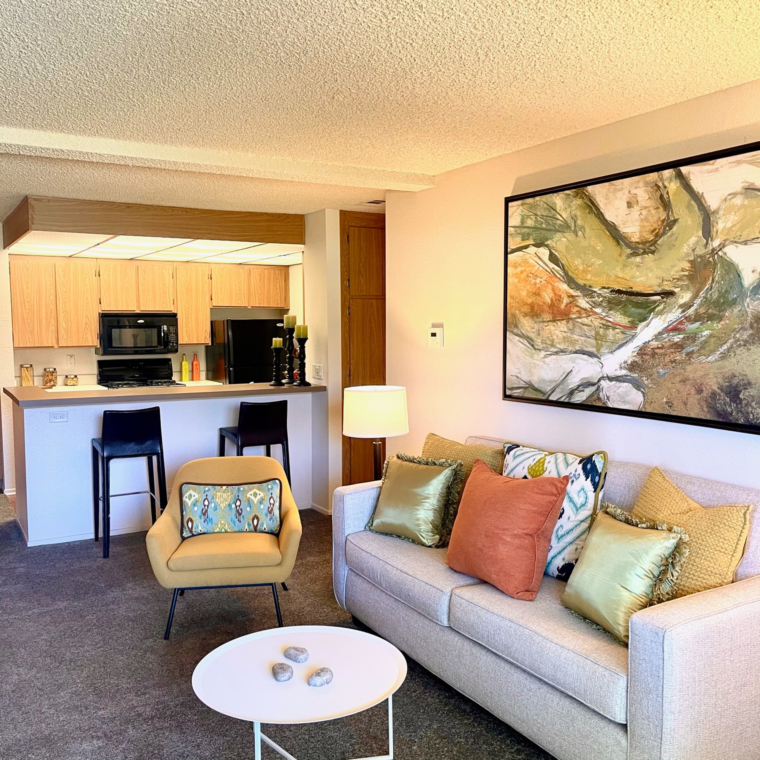 A living room with a couch, chair, and a painting on the wall.