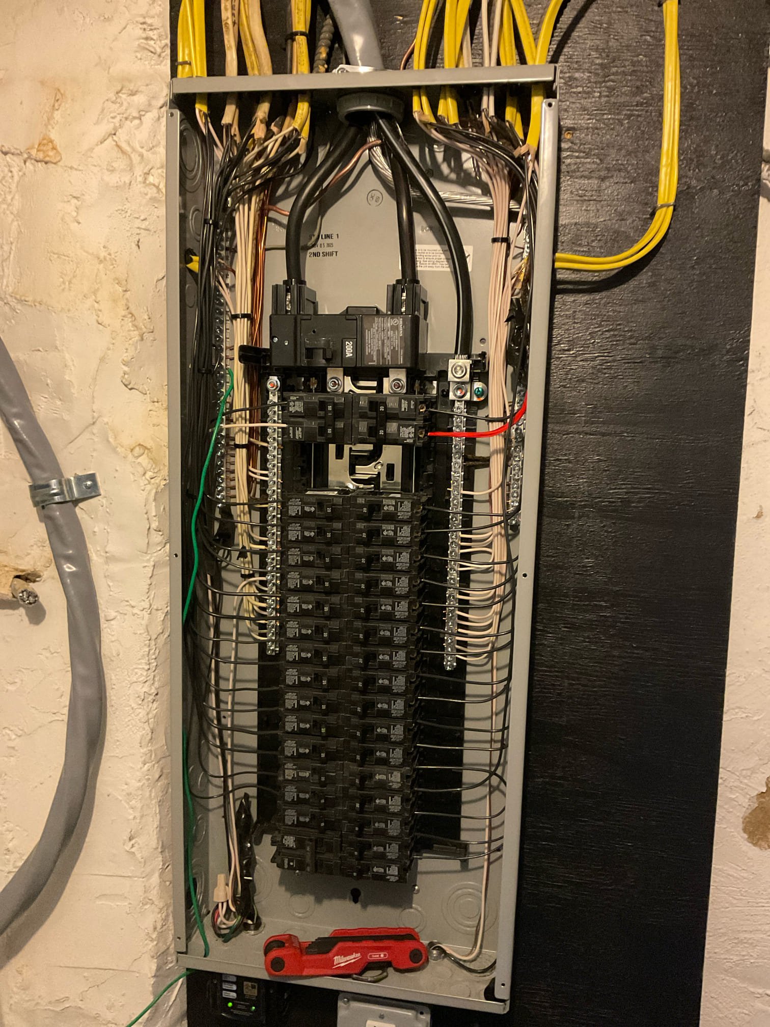 Thomas Edison Electric upgraded this 200-amp breaker panel in a Philadelphia, PA basement. The fully loaded panel features neatly routed circuits, and a Milwaukee tool rests at the base of the enclosure after the job was completed.