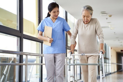 A trained caregiver walks alongside an older adult using a walker, offering guidance and stability. This highlights the mobility support services provided by 7 Sisters Home Care in Mount Vernon, helping individuals move safely and confidently at home or during recovery.