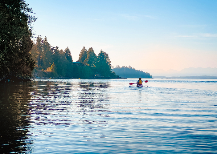 An individual kayaking along a scenic coastline.