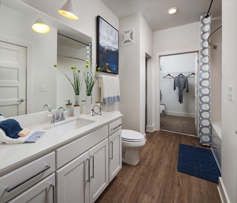 Relax in your Stunning Bathroom with Double Vanity Sinks, Subway Tile Showers with Glass Enclosures and Full Length Mirrors at Echo at North Pointe Center Apartment Homes