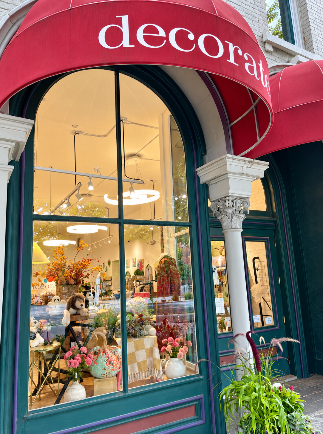 Decorate’s inviting storefront window features colorful home décor, plush toys, flowers textiles, an 