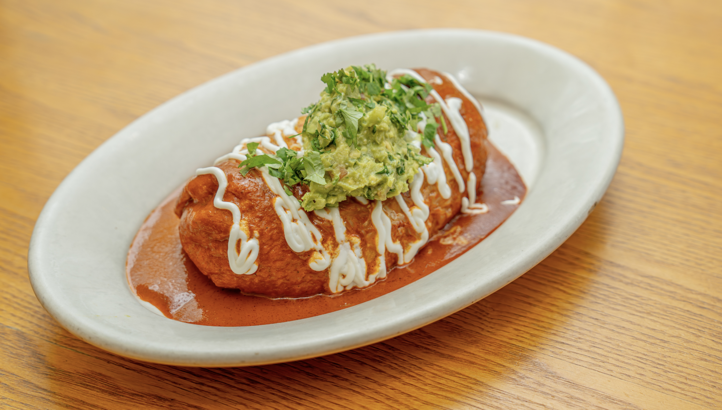 Wet burrito with red sauce, usually under our monthly specials! Flour tortilla stuffed with carnitas, Mexican rice, refried beans, guacamole, and sour cream. Includes your choice of meat.