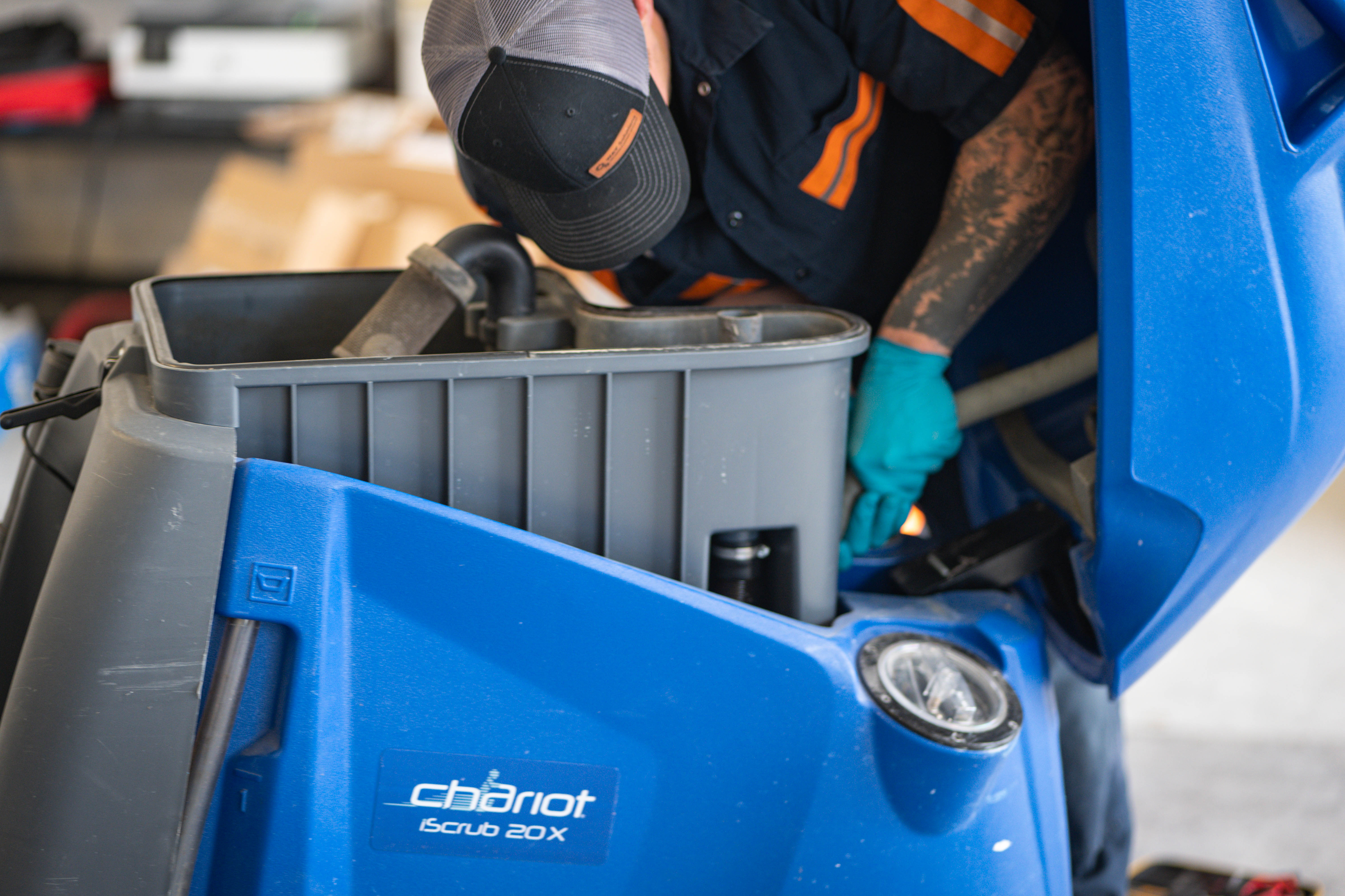 A professional WaySolutions technician inspects the internal recovery tank and plumbing systems of a blue Kärcher Chariot iScrub 20X stand-on floor scrubber. By performing deep internal maintenance in Layton, Utah, our experts prevent vacuum blockages and ensure optimal water recovery for commercial cleaning fleets.