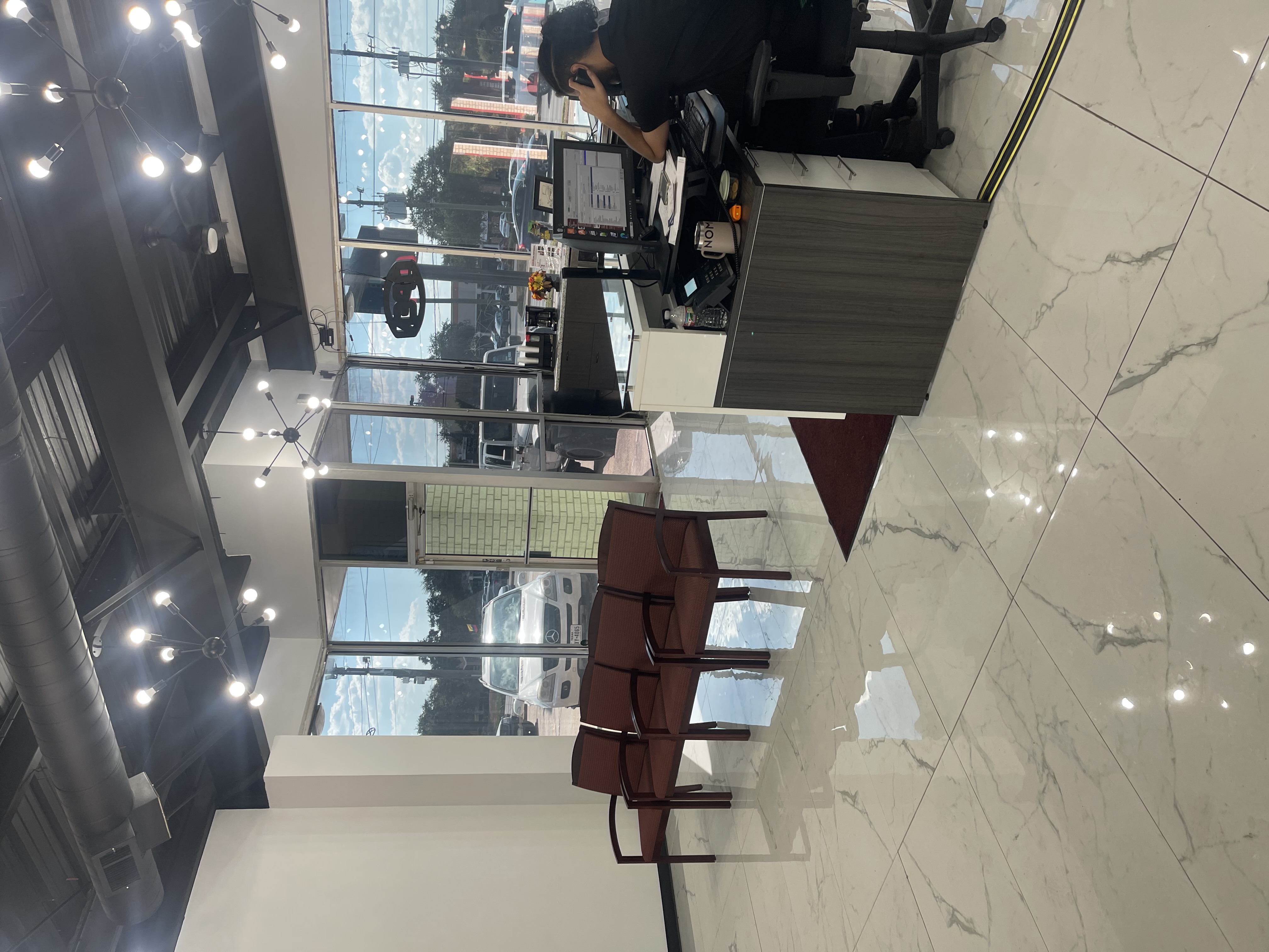 Interior view of the customer waiting area and front reception desk at Yes! Automotive in Houston, Texas, featuring polished tile flooring, comfortable seating, and modern lighting.