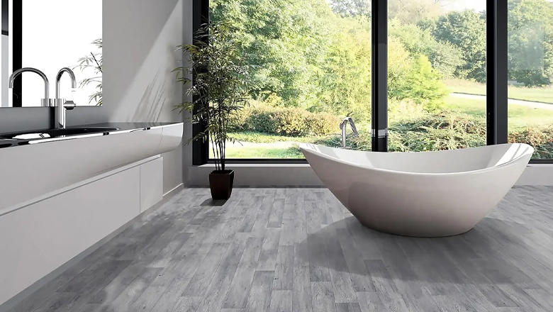 Grey plank effect vinyl flooring in a large modern bathroom with a white freestanding bath tub
