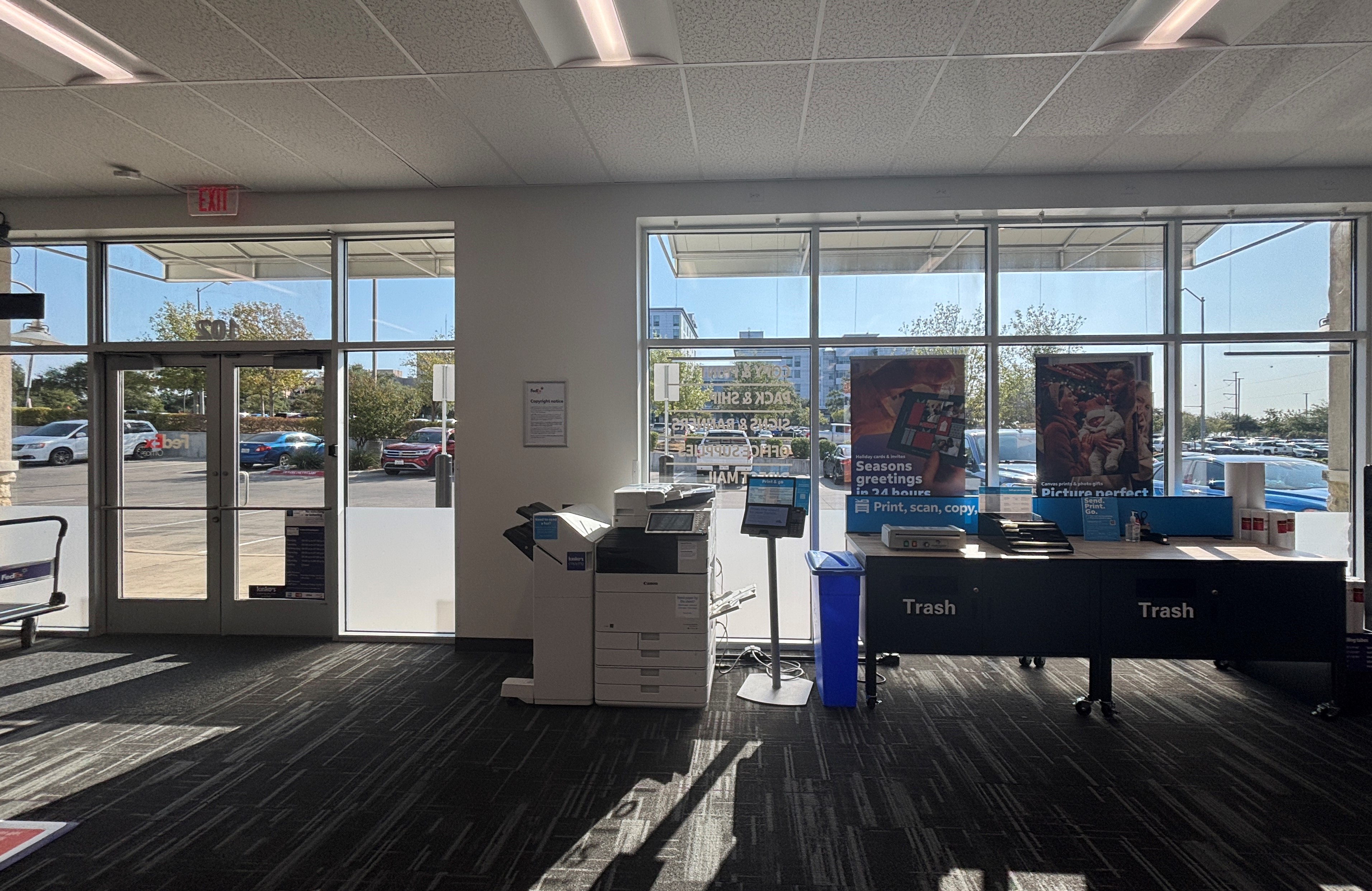 View from the back of the store looking toward the sunlit entrance, showing the self-service printing area and spacious layout.
