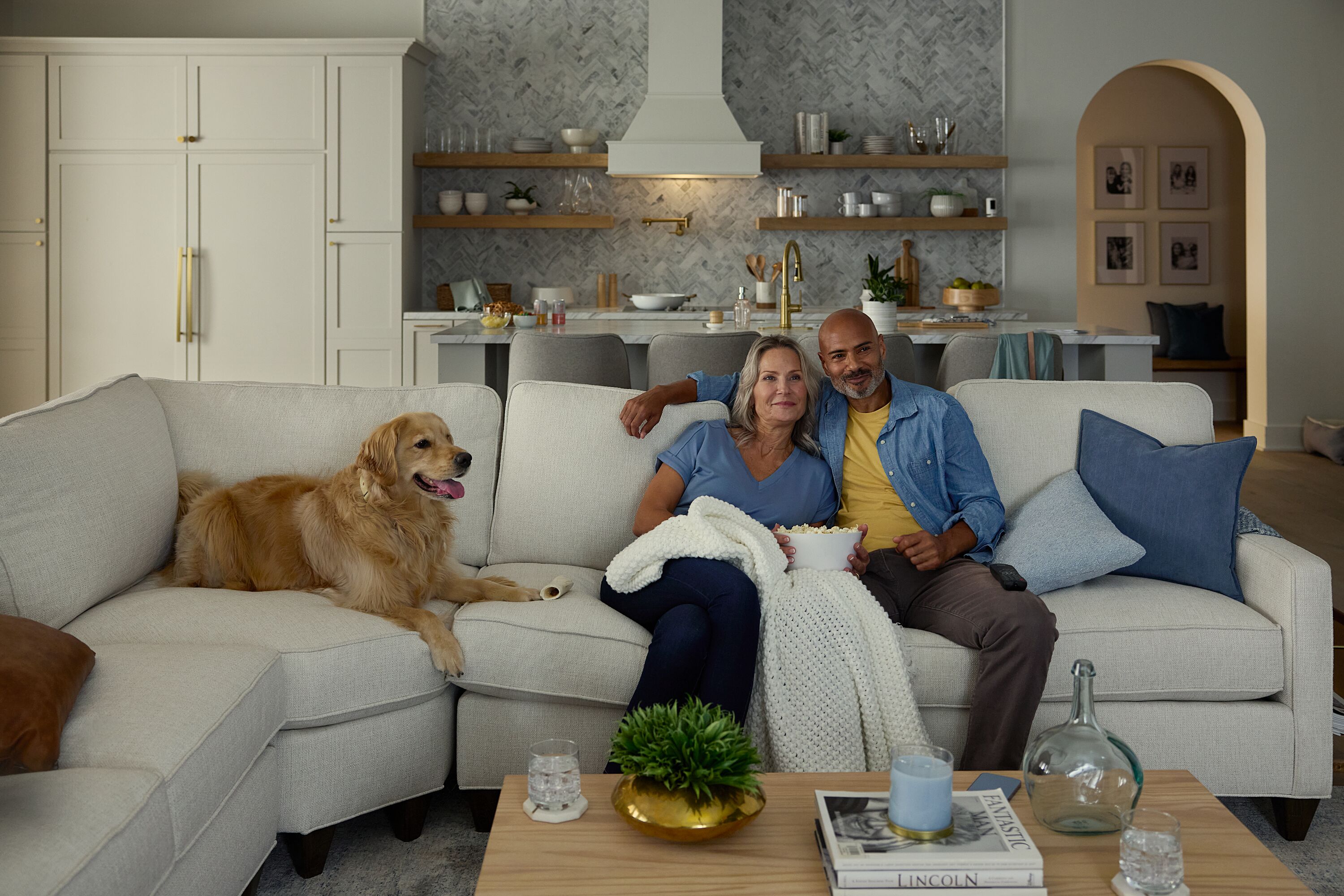 A couple sitting on the couch with their dog.
