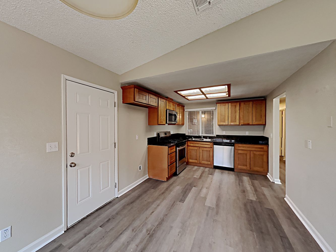 Front door, foyer, and kitchen view with luxury vinyl-plank flooring at Invitation Homes Northern CA.