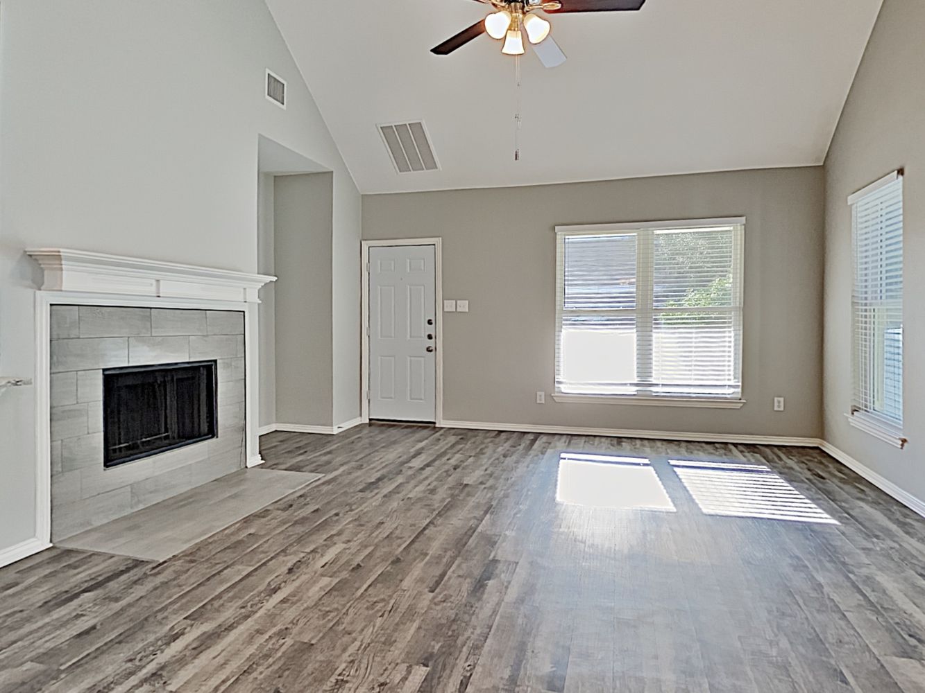 Family room with a fireplace, ceiling fan, and vinyl plank flooring at Invitation Homes Dallas.