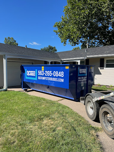 A QC Dumpster Dudes dumpster positioned neatly on a residential driveway, showcasing its utility for home decluttering projects.