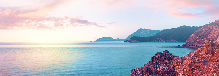 Rugged mountains and the calm ocean at sunrise.