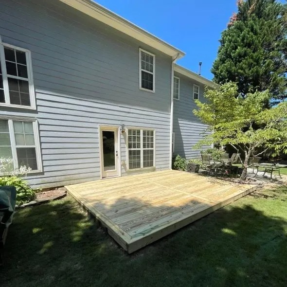 Newly built wooden deck attached to house with surrounding greenery visible.
