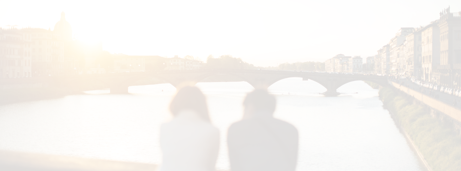 A couple enjoying a scenic sunset view of a bridge over a river.