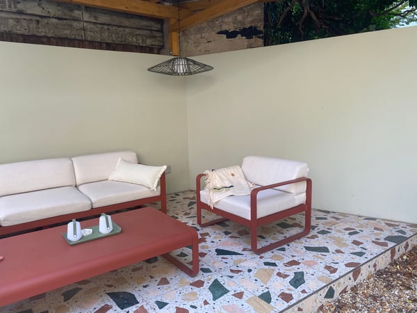Wo zuvor ein verrotteter Schuppen stand, ist nun eine einladende, moderne Lounge entstanden, die zum Verweilen einlädt.

Die bunten Terrazzo-Fliesen wirken wie verstreutes Konfetti, als hätten sie die Reste eines letzten Sommerfestes bewahrt. Die fa...