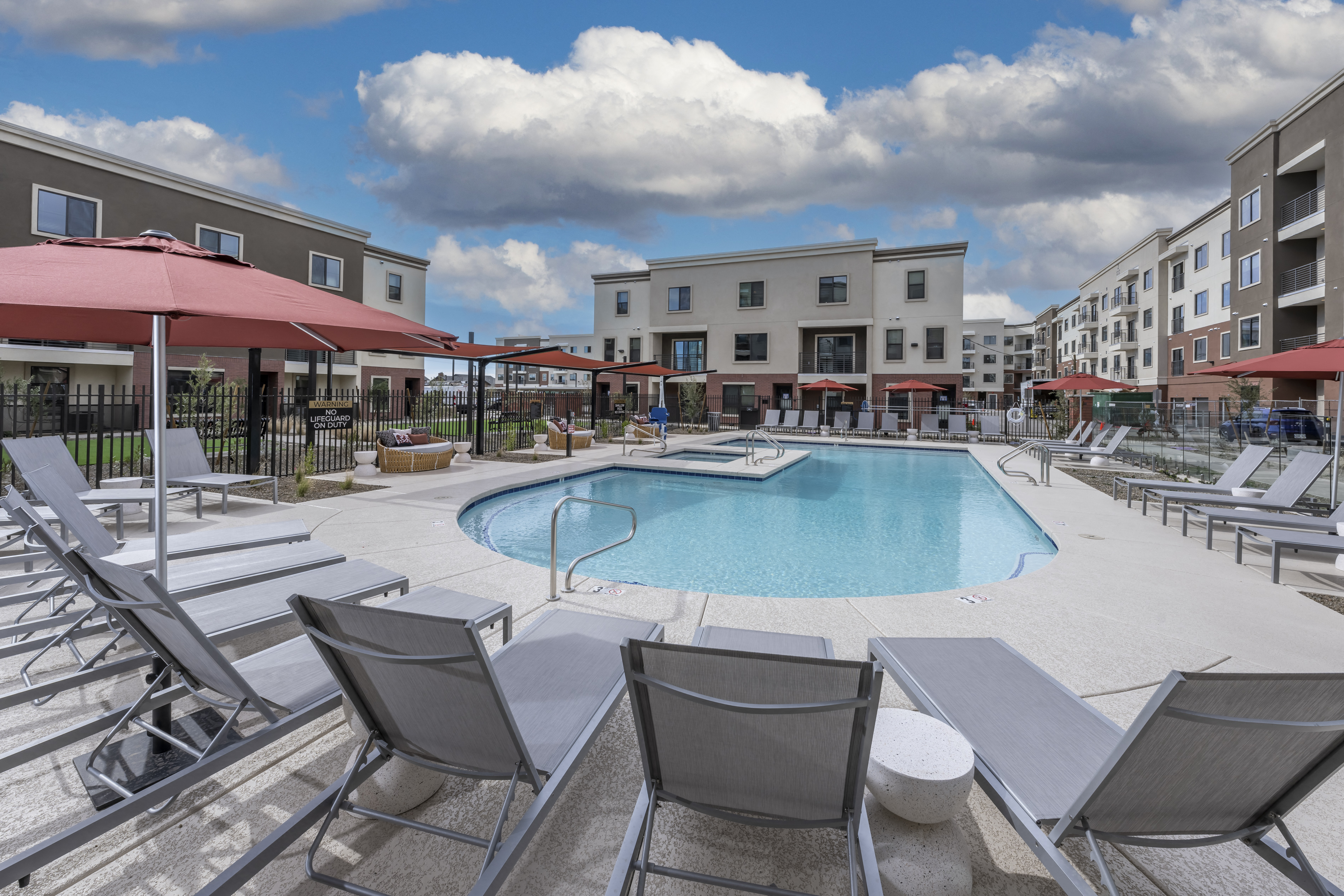 swimming pool with lounge chairs and umbrellas in front of a building